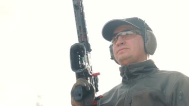 Kafkasyalıların elinde silah tutan bir adamın portresi. Güneş ışınları, tetikçilerin yüzünü arka ışıkla aydınlatır. Güneş ve beyaz gökyüzünün arka planında Yay burcu.