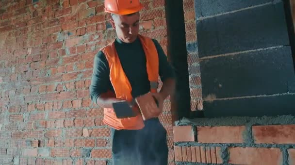 En byggare på en byggarbetsplats lägger tegelstenar i huset. Ventilationskanal för byggtegel. — Stockvideo