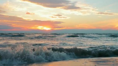 Okyanusta ya da denizde inanılmaz renkli gün batımı. Rahatlama ve uyum zamanı. Deniz dalgaları yavaşça kıyıya geliyor..