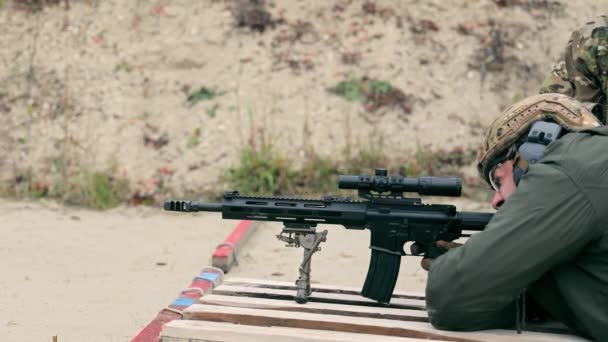 Le dispararon a un francotirador acostado sosteniendo un rifle de francotirador. Luchando y un francotirador acechando en el suelo. Disparo de un rifle de francotirador. — Vídeos de Stock