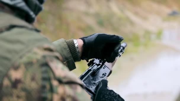A military shooter discharges a machine gun from ammunition. Close-up hand pulls the shutter of the machine and releases the cartridge case from the clip. — Stock Video