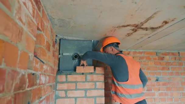 Ο κύριος στο εργοτάξιο χτίζει ένα κανάλι εξαερισμού με κόκκινο τούβλο. Η τοιχοποιία του τοίχου με τσιμέντο και τούβλο. — Αρχείο Βίντεο