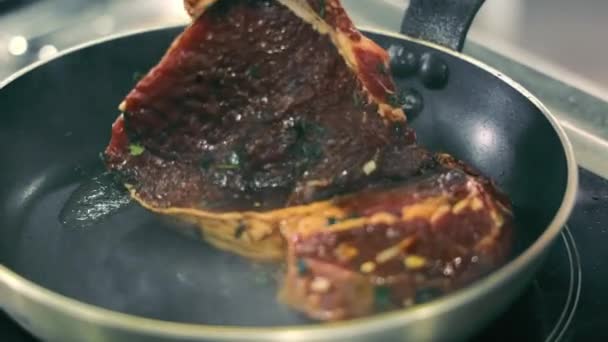 Il cuoco mette un grosso pezzo di succosa bistecca su una padella calda e inizia a friggerlo in olio primo piano.. — Video Stock
