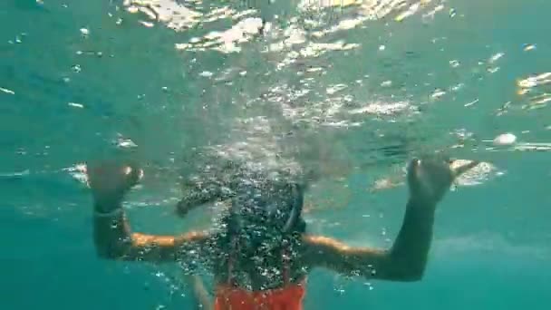 Kind meisje zwemt onder water met een panoramisch masker. Een kind dat bezig is met snorkelen onder water. Het meisje drijft op de oppervlakte van de zee. — Stockvideo
