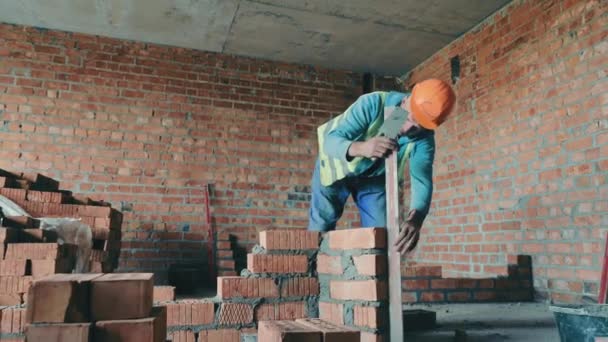 Un constructor en un sitio de construcción pone ladrillos en la casa. Constructor de ladrillo conducto de ventilación. — Vídeo de stock