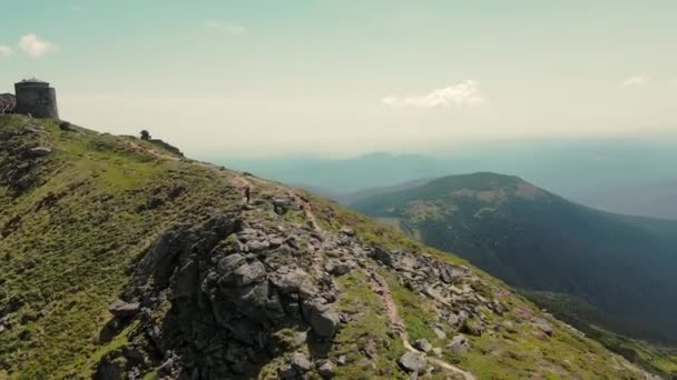 Una turista camina en la cima de una montaña, hermoso paisaje. Una joven conquista altas montañas. Hermoso paisaje de montaña. El cielo, las cimas de las montañas y una mujer-turista caminando sobre una roca — Vídeo de stock