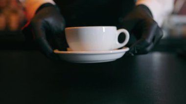 Restorandaki garson kameranın önüne ya da müşterinin önüne bir fincan sıcak kahve ya da çay koyar. Bir fincan kahve ya da çay içer misin?.