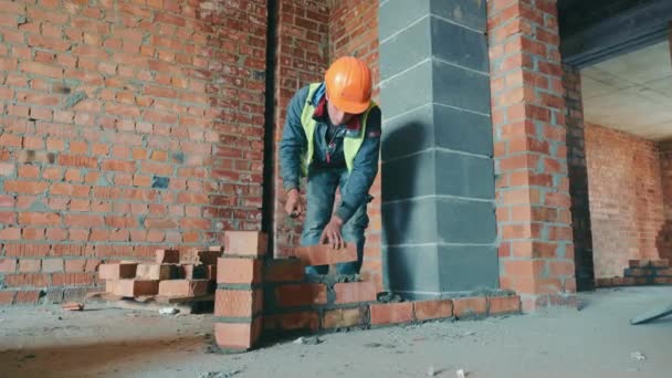 Mästare lägger tegelstenar och bygger husets mur. Byggnadsarbeten. Konstruktion av invändiga skiljeväggar av rött tegel. — Stockvideo