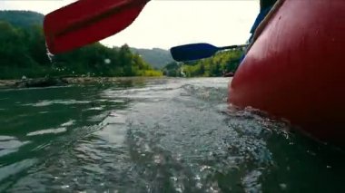 Rafting dağda nehir raftinginde. Kürekle yakın mesafeden kürek çeken bir sporcu. Dağ nehrinde kürek çekmek. Bir teknede aktif dinlenme.