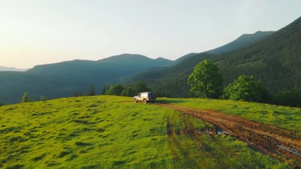 Vzdušný výhled na úsvit na vysočině. SUV stojí na prašné cestě v horách. Turistika v horách. Východ slunce v horách. Krásné ukrajinské Karpat — Stock video
