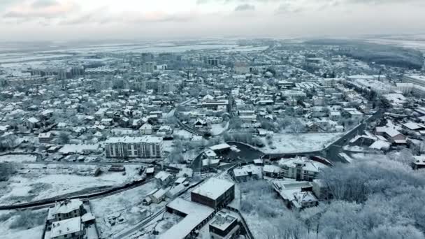 Krajobraz pokrytego śniegiem miasta w zimowy wieczór pochmurny dzień. Lot nad małą wioską na Ukrainie. Domy i ulice są pokryte śniegiem — Wideo stockowe