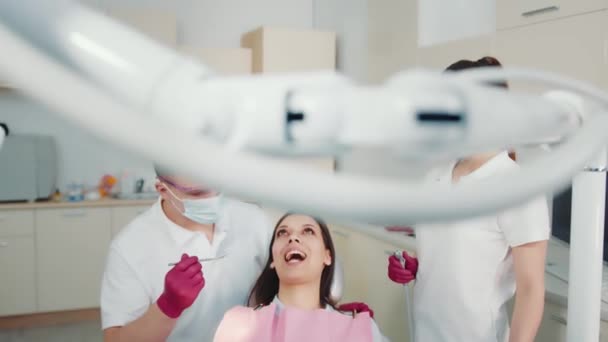 El dentista junto con el asistente examina los dientes de los pacientes. Examen de la mandíbula y los dientes en la consulta del dentista en la clínica dental. — Vídeos de Stock
