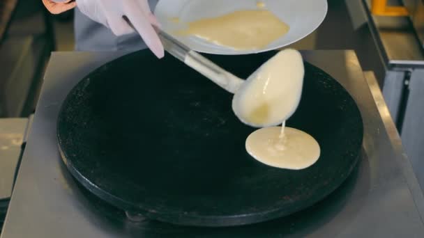 Pannenkoeken bakken op een hete metalen pan. Straatvoedsel en fastfood. De kok giet het pannenkoekenmengsel in de pan. — Stockvideo