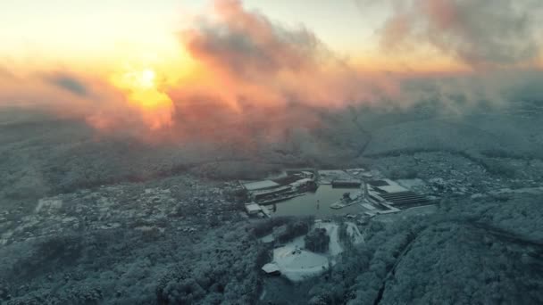 Winter landscape. Flight over the village at sunset. Flying through the clouds illuminating the sun. — Stock Video