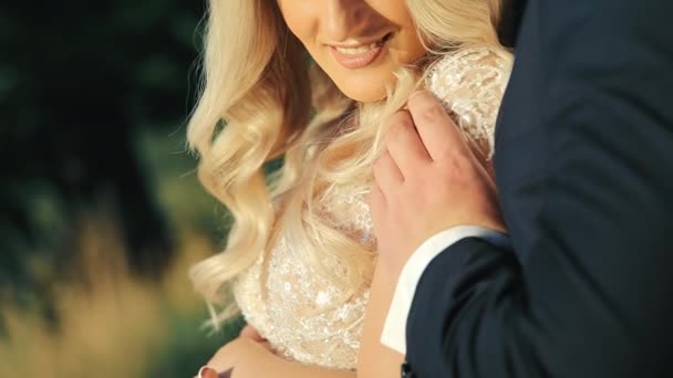 Widok na blond włosy panny młodej i pana młodego trzymających się za ręce, przytulających się w dniu ślubu. Close up widok na ślub para delikatnie trzymając się za ręce, panna młoda uśmiechnięta, jej pierścionek jest widoczny. Pojęcie ślubu — Wideo stockowe
