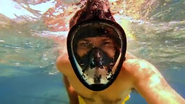 수영 마스크를 쓴 젊은이 가 물 속에서 셀카를 복용하는 모습. 노란 수영복을 입은 백인 남성 이 셀카 스틱을 들고 푸른 물에 스노클링을 하고 있습니다. 물의 활동에 대한 개념 — 비디오