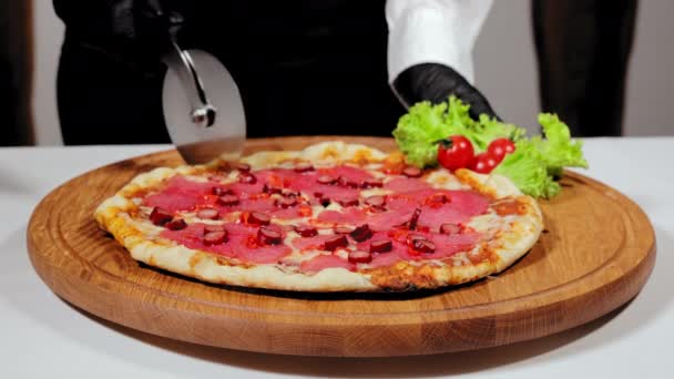 Kocken skär pizzabitar. Hemlagad pizza bakad på ved med korv är uppdelad i bitar med kniv. — Stockvideo