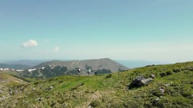 Dağın tepesinde duran dört turist. Dağlarda yürüyüş. Resimli Karpat Dağları 'nın havadan görünüşü. Turist grubu dağın zirvesine çıkarken dinleniyor. Turistler