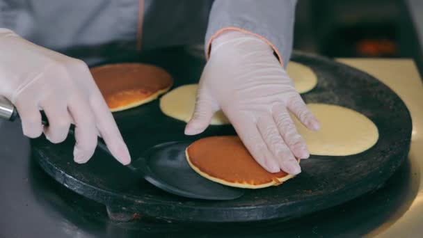 Straatvoedsel koken. De vrouw bakt pannenkoeken op een kookplaat en legt de afgebouwde schotel op een bord. Snel pannenkoeken bakken. — Stockvideo