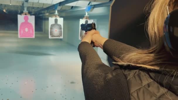 Mujer disparando a un objetivo con una pistola en un campo de tiro. Mujer entrenando para golpear a un objetivo con una pistola. Capacitación de mujeres policías. — Vídeos de Stock