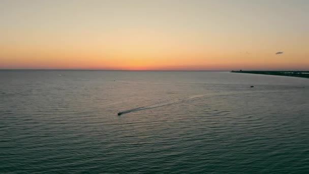 Vista aérea Pôr do sol no mar e na praia a partir de uma vista de olhos de pássaros. Barcos a motor navegando no mar. Praia da cidade do mar. — Vídeo de Stock