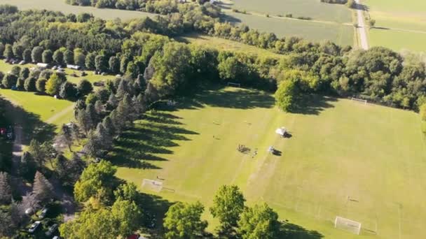 Voetbalveld op het platteland, midden in de bossen op zonnige dag. Luchtfoto van drone van lokale voetbalveld op landelijke locatie, met dik bos rond gebied. Begrip bestemming — Stockvideo