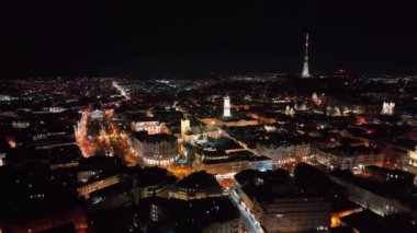 Geceleri şehrin üzerinde uçan bir hava aracı. Ukrayna 'daki Gece Şehri Lviv. Aydınlanmış sokaklar ve araba trafiği. Büyük şehir gecesinin gece hayatı.