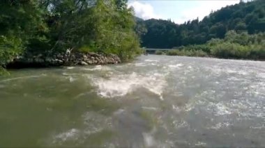 Dağ nehri akıntısı hareketli rafting yaparken tekneden nefes kesici görünüyor. Aşırı rafting sırasında köpüren suyun ön görüntüsü, arka planda manzarası olan. Ekstrem spor anlayışı