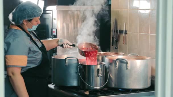 Gotowanie dla ludzi o niskich dochodach. Kucharka gotująca w aluminiowym pojemniku. Czerwona zupa dla biednych. — Wideo stockowe
