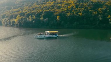 Üzerinde mavi ve sarı bayrak olan feribot manzaralı geniş, dalgalı bir nehirde yüzüyor. Dinyester nehrinde Ukrayna 'ya turist gezisi