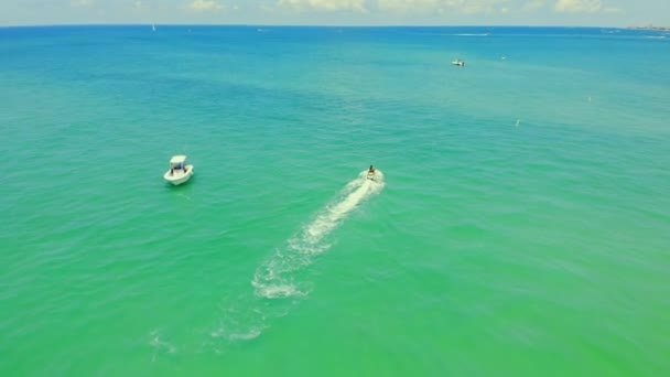 Rychlý motorový člun plující v modré lesklé mořské vodě s bílými víry za sebou. Letecký pohled z dronu plachetnice na hladině teal oceánu v létě. Koncepce vodních aktivit — Stock video