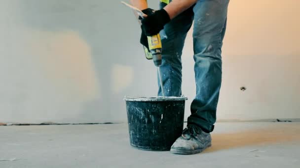 Plasterer painter construction worker mixes construction mixture in a bucket. Construction and renovation of the room. Indoor construction work. — Video Stock