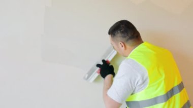 Repair work in the room. Plasterer painter construction worker plasters the wall with a plaster spatula. Plastering and leveling of unevenness on a wall by means of finishing plaster.