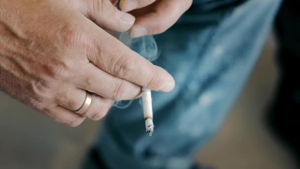 Un hombre sosteniendo un cigarrillo humeante en su mano de cerca. Malo estilo de vida y malos hábitos. Fumar cigarrillo en la mano de los fumadores. — Vídeos de Stock