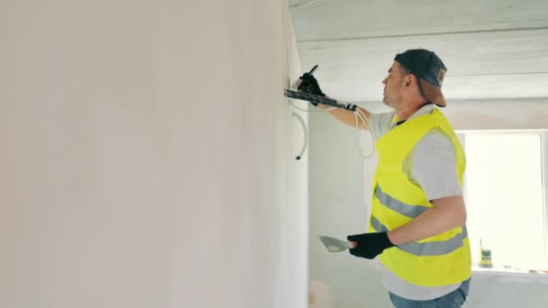 Repair work in the room. Plasterer painter construction worker plasters the wall with a plaster spatula. Plastering and leveling of unevenness on a wall by means of finishing plaster. — Stockvideo