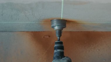 En üstteki inşaat işçisinin görüntüsü duvarın altına bir delik açıyor. Elektrik prizi için delik düzeyi lazerle ayarlanıyor.