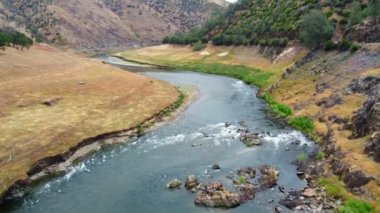 Kaliforniya dağlarındaki bir nehrin üzerinden uçan bir hava aracı. Yazın dağların arasından akan kuraklıktaki küçük bir nehir. Sığ bir dağ nehri