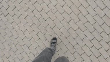 Asfalt üzerinde yürüyen erkek ayağının en üst görüntüsü. Yol boyunca bir yürüyüş. Erkek ayağı için sandaletler