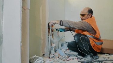 Tamirat sırasında tesisatçı, evdeki tadilat sırasında banyoya su boruları döker.