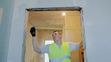 Ana kapı aralığını ölçer. Bir apartman inşaatı ve onarımı. Kapı aralığını ölçüyorum.