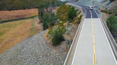 A mobile home traveling in the mountains of California. Flying over a bridge and a road where a popular tourist route passes