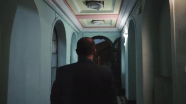 Silhouette of a man in the dark entrance of a house walking. Rear view of a man