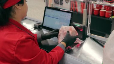 The cashier at the supermarket checkout scans the bar code of the product. The seller enters information about the purchase into the computer.