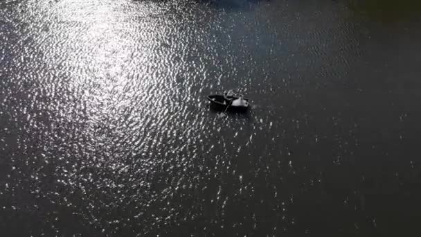 大きな湖の水に反映されている太陽の素晴らしいグレアの背景に花嫁とボート — ストック動画