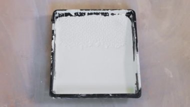 A close-up of a painter putting paint on a paint roller