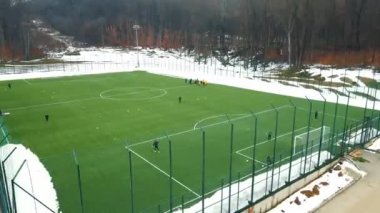 A football field in winter from a birds eye view. Training, warm-up and running of football players