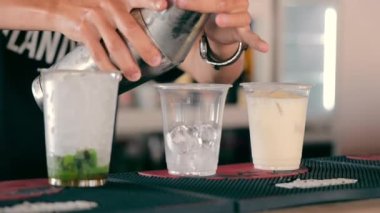 Bir barmen tek kullanımlık bardakta buzlu kokteyl hazırlar. Plastik kutuda bir kokteyl..