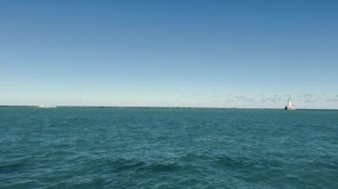 Michigan Gölü manzarası ve ufukta küçük bir deniz feneri. Gündüzleri büyük göl ve manzara. Bulutsuz mavi gökyüzü. Statik çekim ellerden yapılmış.