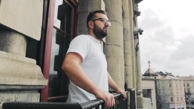 Balkondaki sabah adamı şehre bakıyor. Bir adam balkonda duruyor.