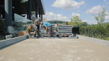 Döşeme döşemeleri. Usta adamlar kaldırım taşlarından yol yapar.